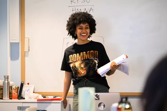 Hanna står vid en white board, skrattar och ser på en publik. 