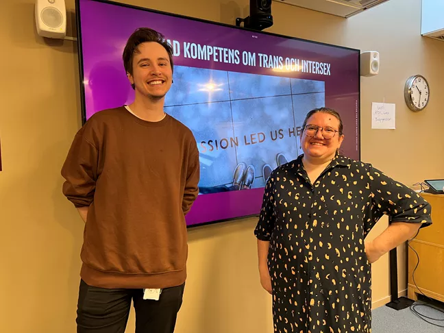 Christoffer och Lo står framför en powerpoint som det står kometens om trans och intersex på. 
